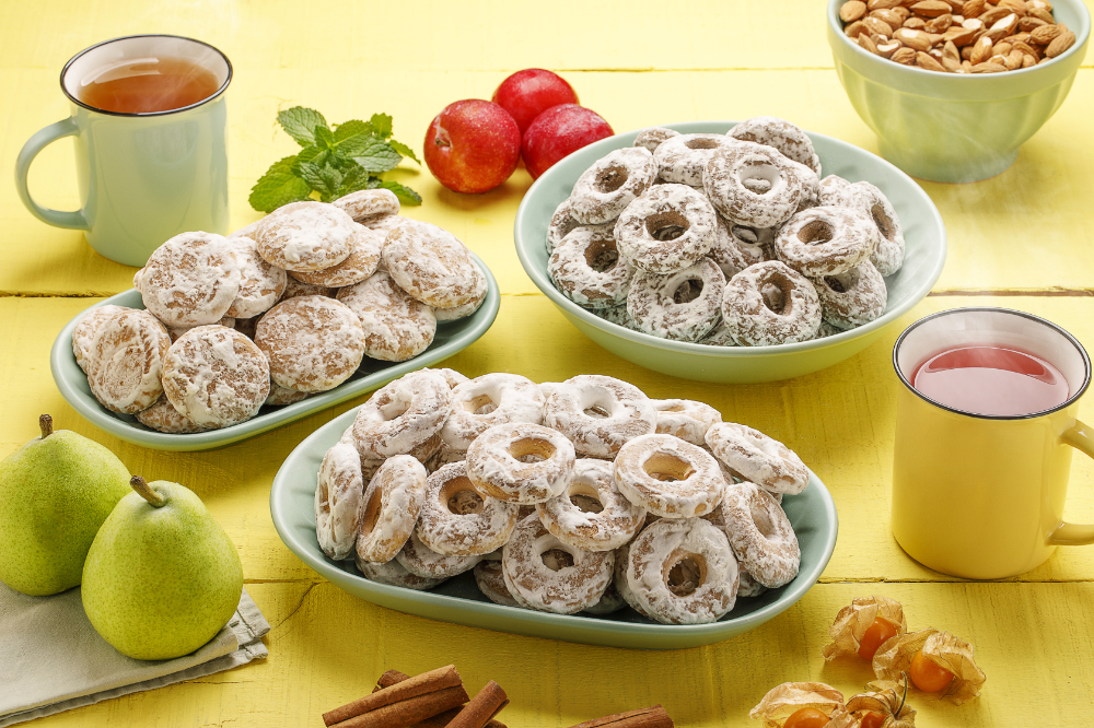 Pratos com biscoitos de pão de mel e rosca de calda, dispostos ao lado de xícaras de chá
