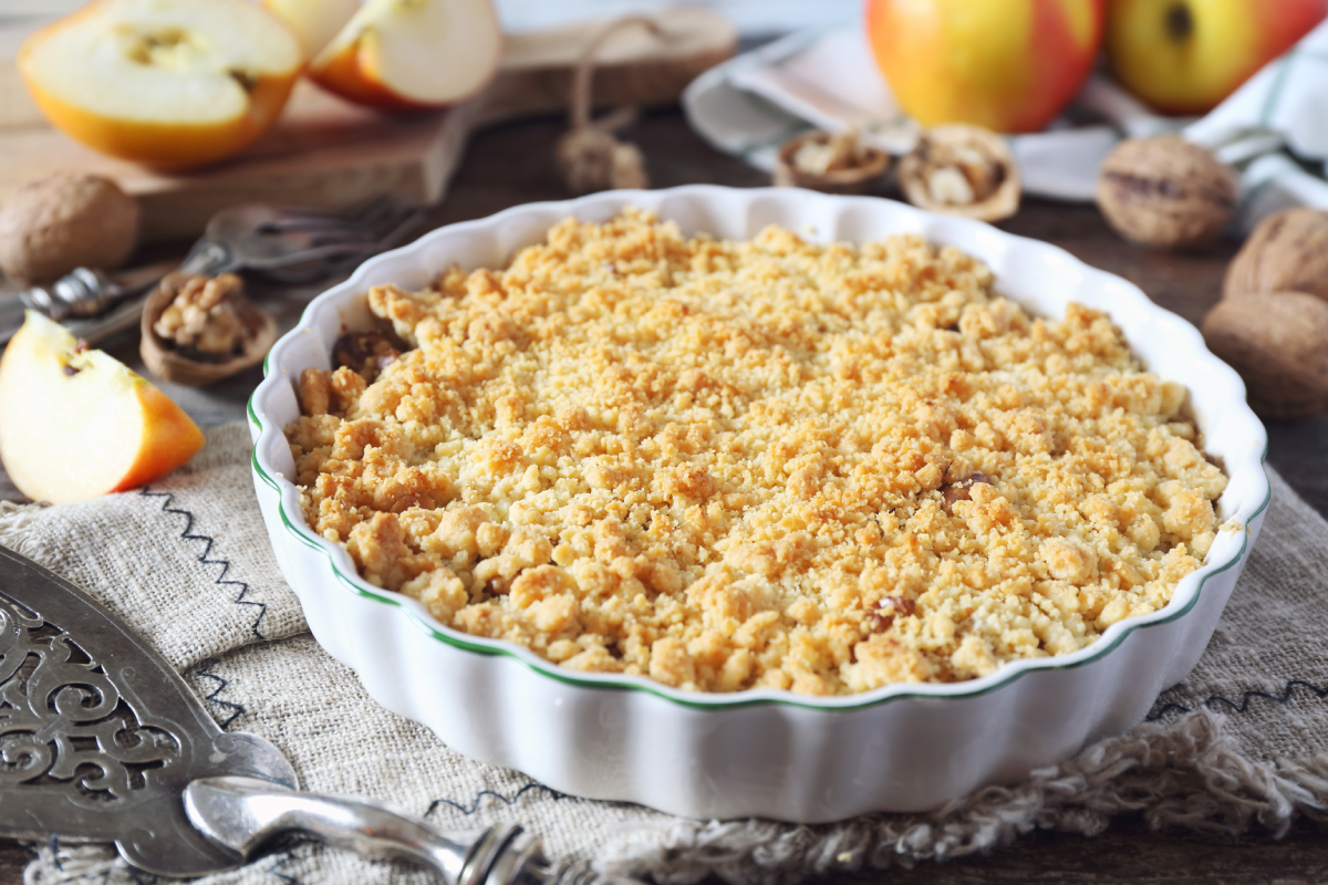 Crumble de maçã assado, com cobertura de biscoito maisena, sobre fundo desfocado.