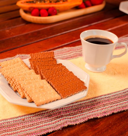 Prato branco com biscoitos Doble, servidos sobre mesa de madeira ao lado da xícara de café