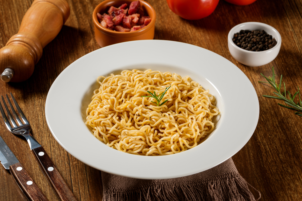 Tigela de macarrão instantâneo sabor galinha, com alecrim, sobre mesa de madeira.