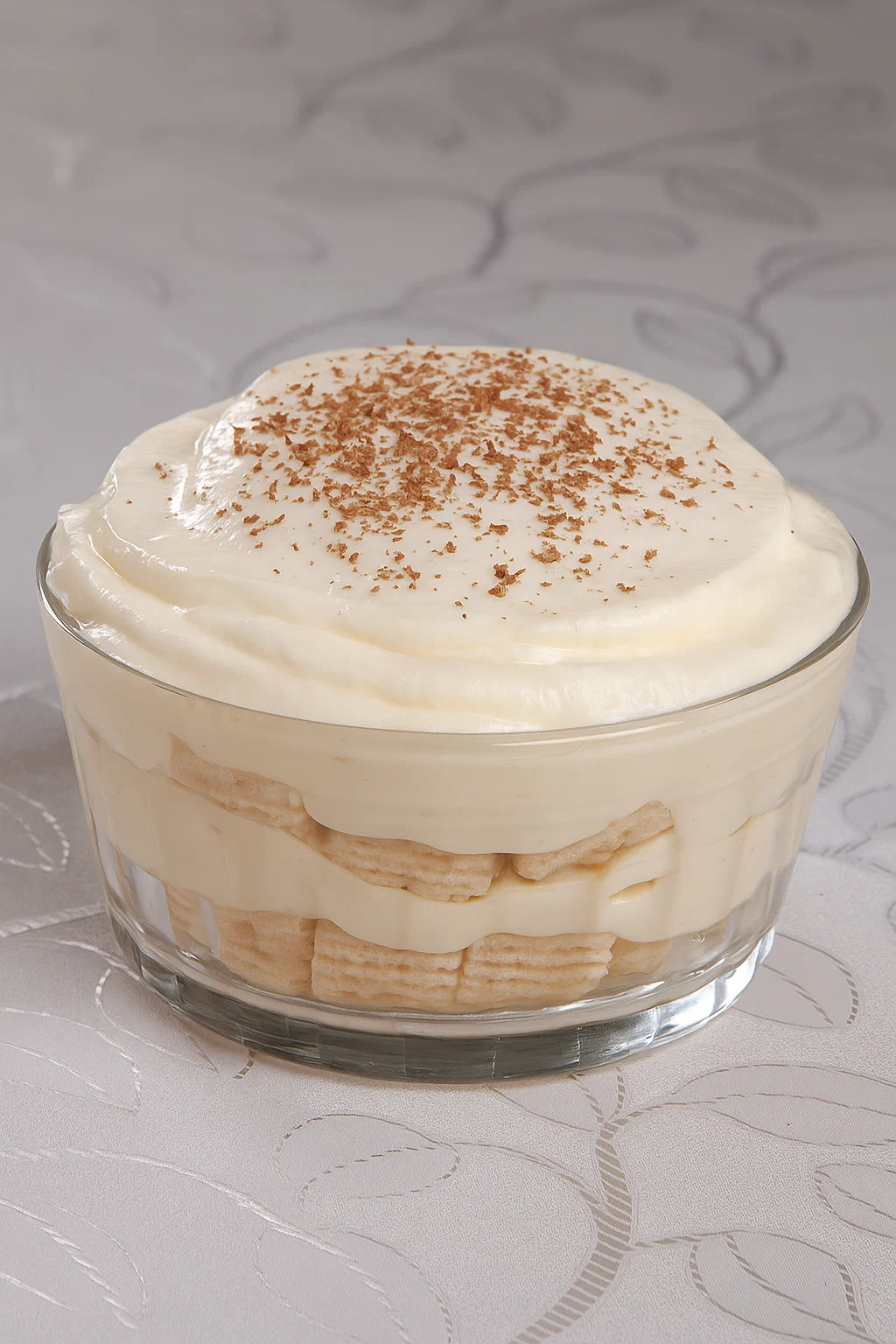 Pavê de limão e biscoito wafer, polvilhado com cacau em pó, sobre mesa clara.