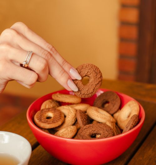 Pote vermelho de rosquinhas tradicionais, sobre mesa de madeira em ambiente iluminado