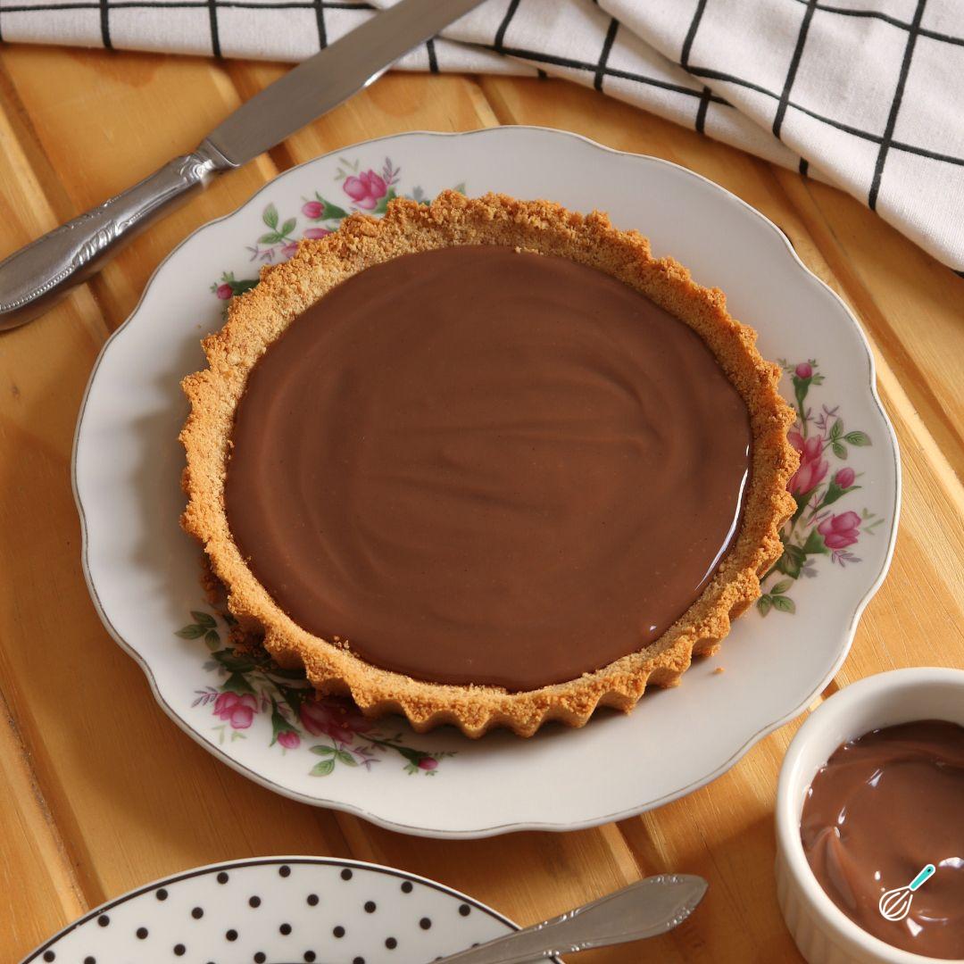 Torta de biscoito Maria e recheio de brigadeiro, servida em prato branco sobre mesa de madeira.