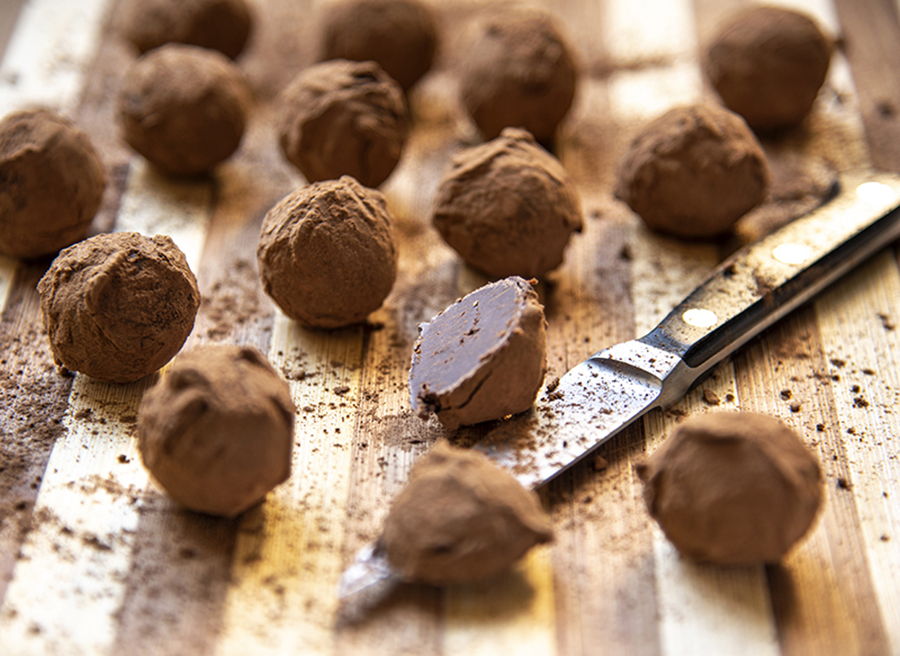 Tábua com trufas de biscoito recheado sabor chocolate, cobertas em cacau em pó.