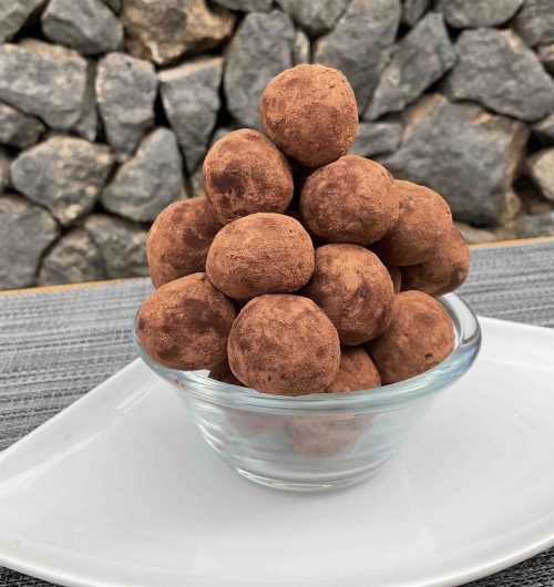 Pote com trufas de tiramisù feitas com biscoito champanhe, cobertas com cacau em pó e dispostas em torre.