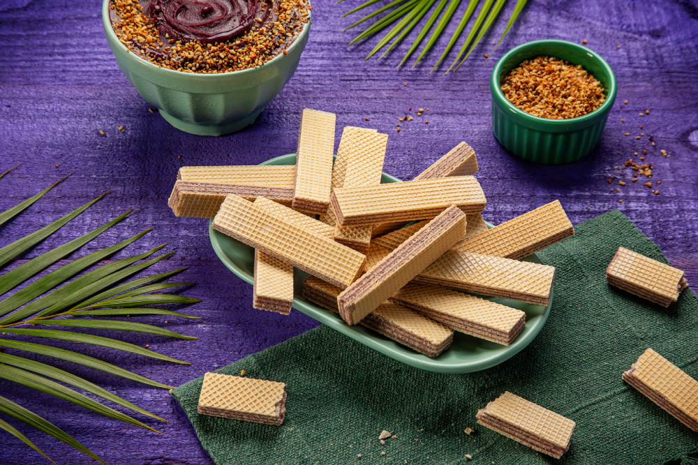Wafer sabor açaí dispostos em prato, sobre fundo roxo.