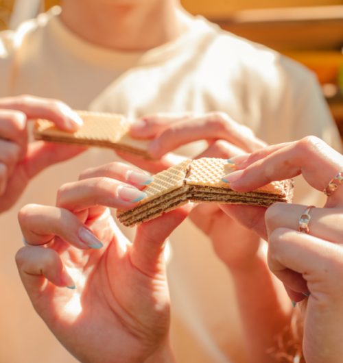 Casal junto compartilha wafers Ninfa sabor chocolate, em ambiente claro.